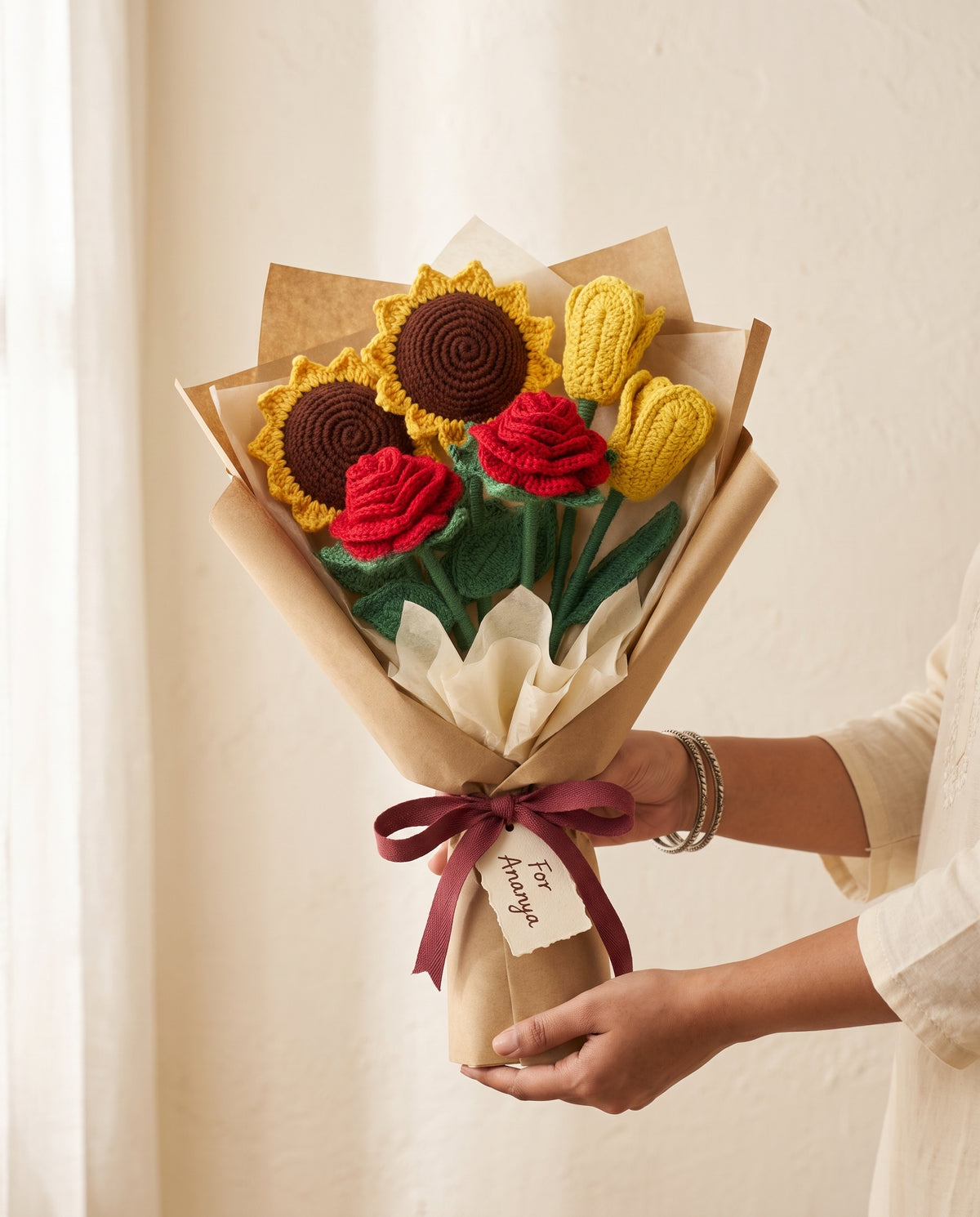 Wrapped crochet bouquet of roses, sunflowers and tulips held in two hands