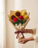 Wrapped crochet bouquet of roses, sunflowers and tulips held in two hands