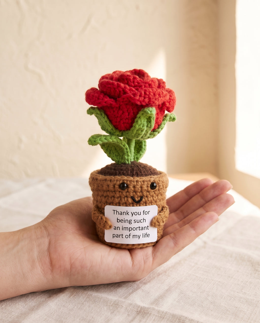 Crochet rose pot desk buddy held in a palm to show its size