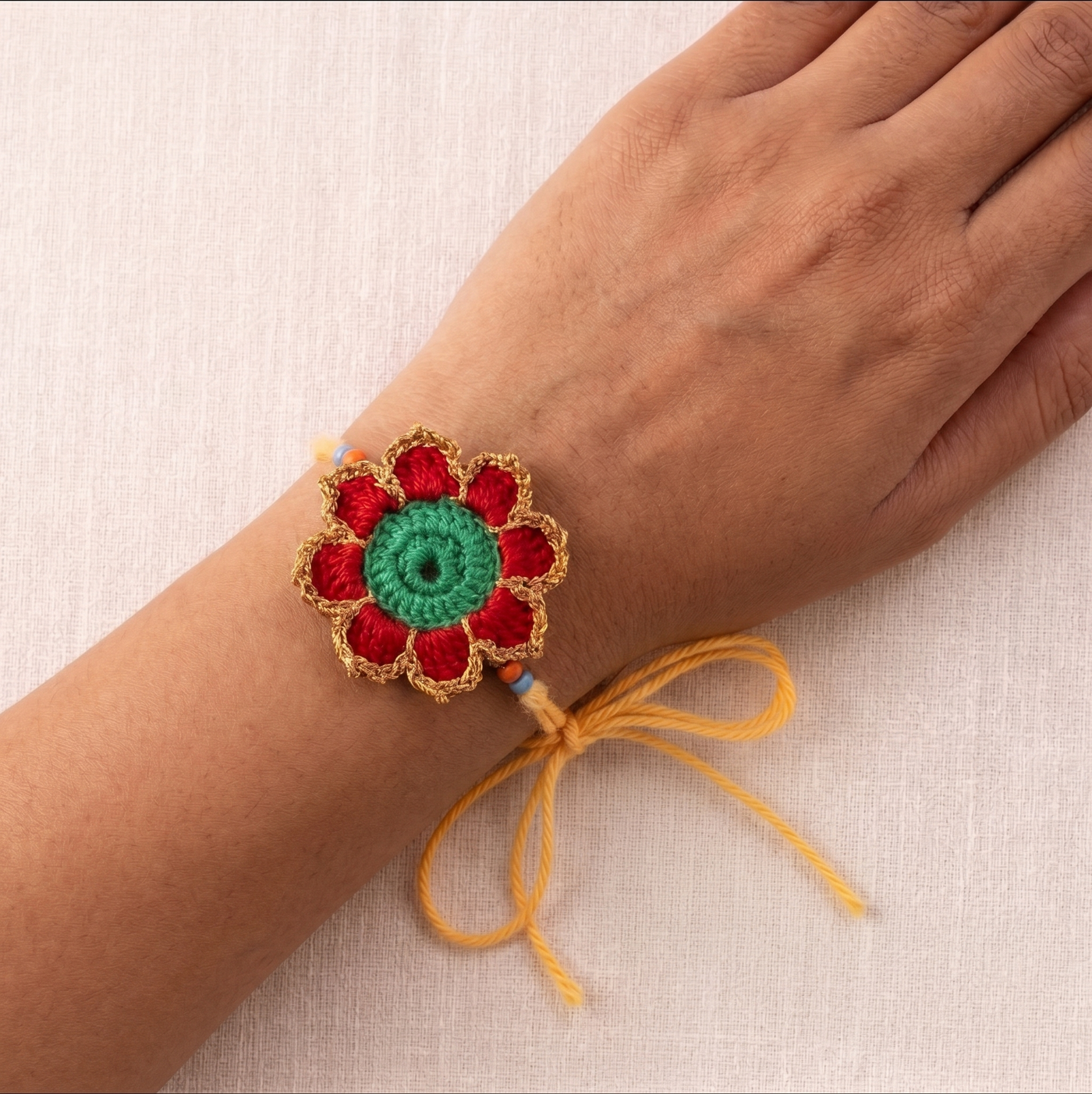 Handmade red green and gold crochet marigold flower rakhi with pearl for Raksha Bandhan