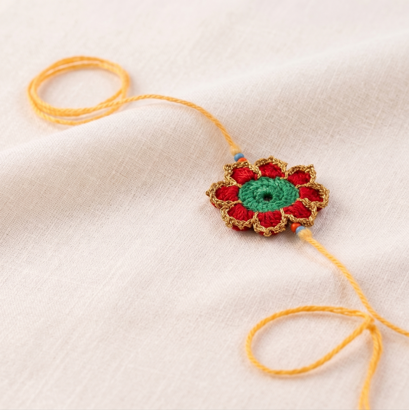 Handmade red green and gold crochet marigold flower rakhi with pearl for Raksha Bandhan