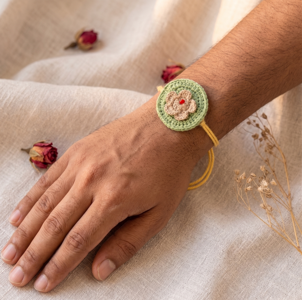Handmade sage green crochet disc rakhi with beige flower and red bead