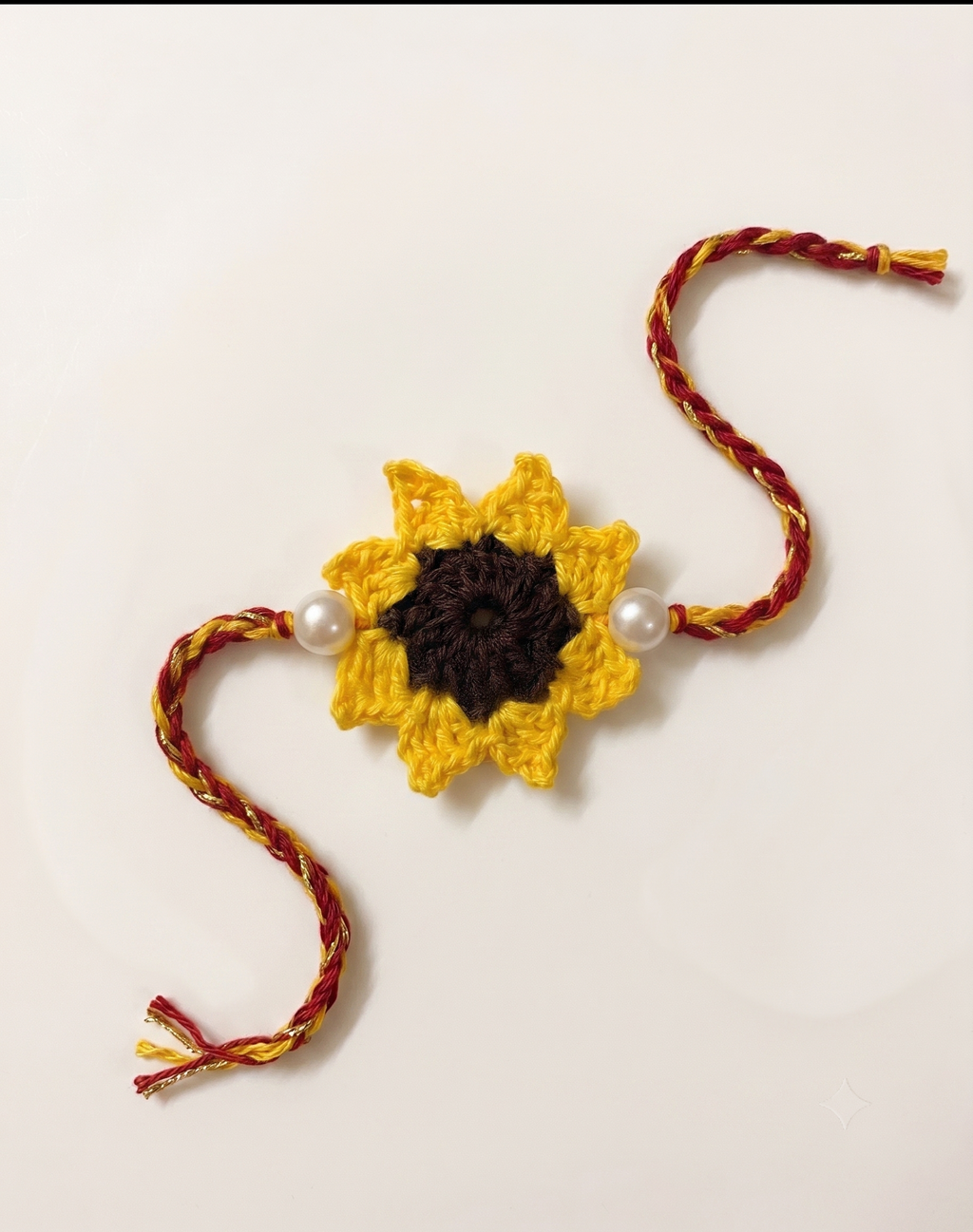 Handmade yellow crochet sunflower rakhi with brown centre and twin pearls