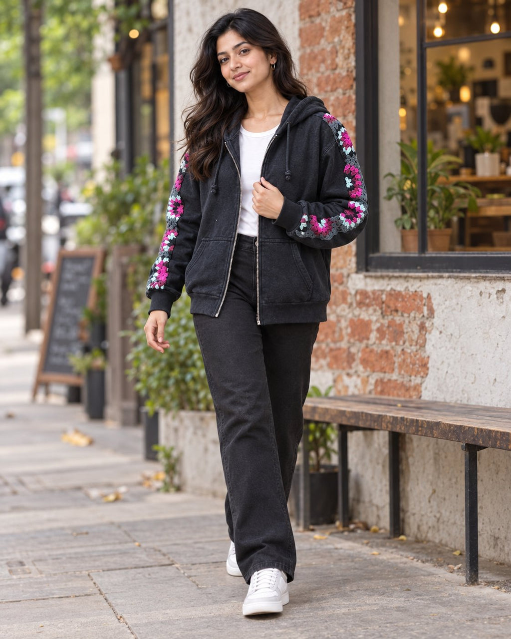Woman wearing a charcoal granny square crochet zip hoodie on a city street