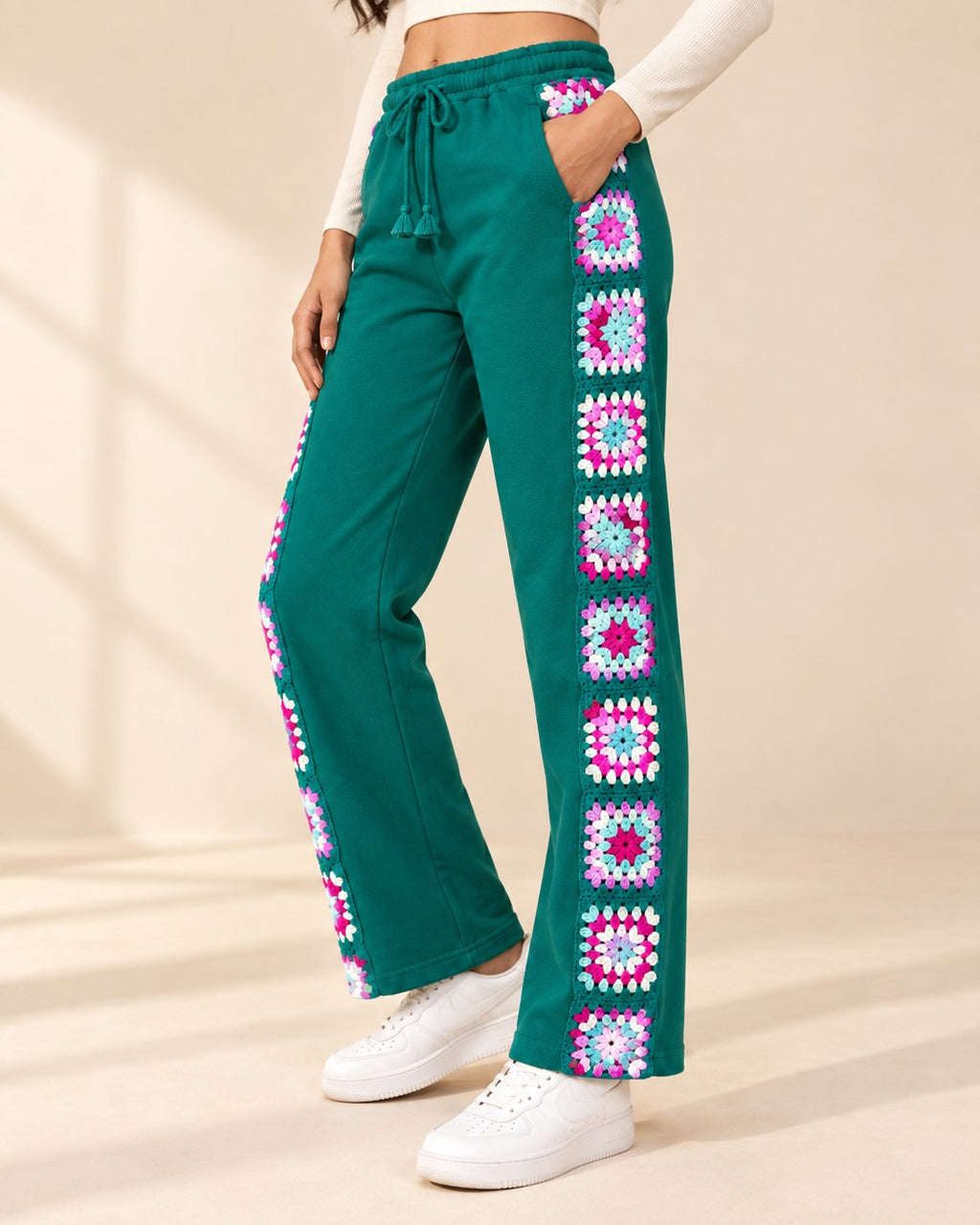 Side view of teal wide-leg sweatpants showing the full column of crocheted granny squares